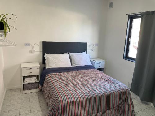 a bedroom with a bed with a striped comforter and a window at Hermoso departamento panorámico en Rio Gallegos in Río Gallegos