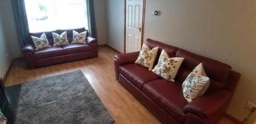a living room with two leather couches and a rug at Laurelbrook Town House in Magherafelt