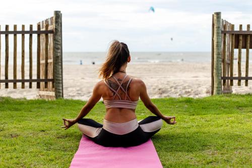 une femme faisant du yoga à la plage dans l'établissement Vila Beijú BARRINHA - Frente Mar!, à Barrinha