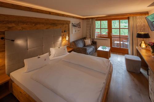 a bedroom with a large white bed and a living room at Das alpine Lifestyle Berghotel Madlener in Damuls