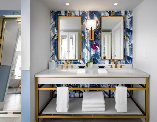 a bathroom with two sinks and two mirrors at Cadillac Hotel & Beach Club, Autograph Collection in Miami Beach