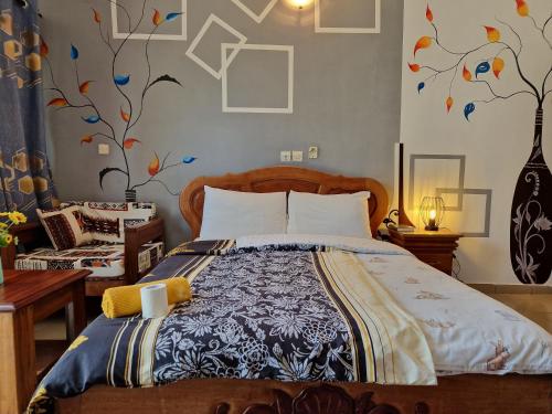 a bedroom with a bed with a tree mural on the wall at Hotel Madou Grand Bassam in Grand-Bassam