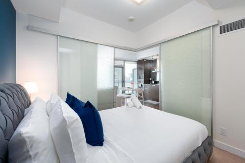 a bedroom with a white bed with blue pillows at Downtown Apartments 10 in Toronto