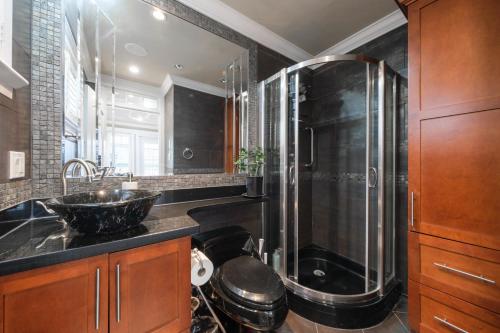 Luxurious 8-Bedroom Villa in Central Vancouver في فانكوفر: حمام مع دش زجاجي ومغسلة