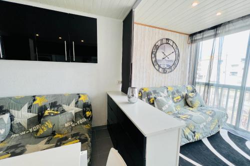 un salon avec un canapé et une horloge au mur dans l'établissement Los Amigos - Studio confort proche de la plage, au Grau-du-Roi