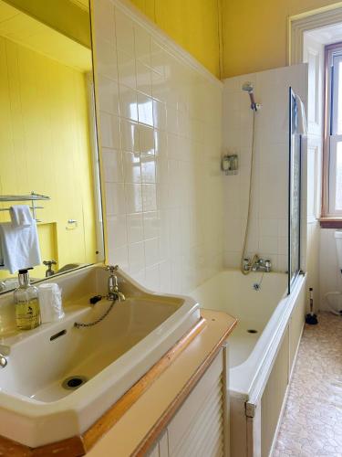 a bathroom with a sink and a tub and a mirror at Rosehall Hotel in Edinburgh