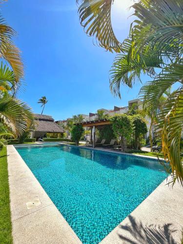 a swimming pool in front of a villa at Departamento planta baja con alberca a 5 min de playa! in Manzanillo