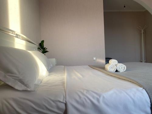 Una cama blanca con dos toallas enrolladas. en Байсеитрум, en Semey