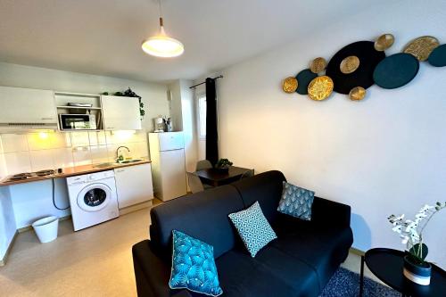 a living room with a black couch and a kitchen at Les Naïades F27 - 1 bedroom for 4 people ! in Avène