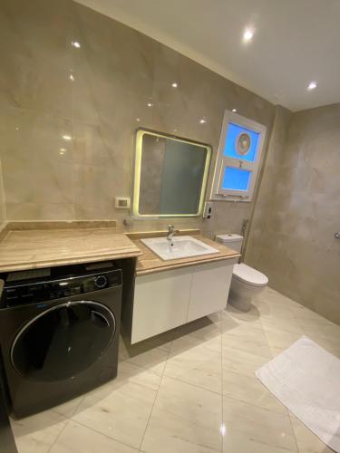 a bathroom with a sink and a washing machine at شقة فندقية عائلية بجانب المطار منتجع اوشن بلو in Cairo