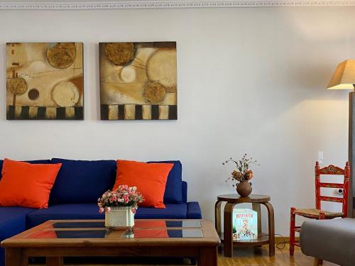 a living room with a blue couch with orange pillows at El Jardín de la Morena by ARoom in León