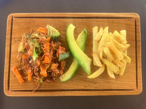 a wooden plate of food with a sandwich and fries at Hostal Del Cielo in Medellín