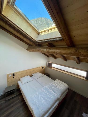 un lit dans une chambre avec une grande fenêtre dans l'établissement La MaiZon du Bois 1 er étage, à Champagny-en-Vanoise