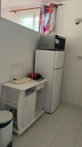 uma cozinha com um frigorífico branco e uma mesa com um computador em Appartement F2 ROSALINDA em Les Abymes