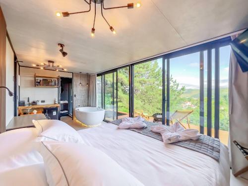 une chambre avec un grand lit blanc avec une grande fenêtre dans l'établissement CNB - Cabanas Vista Serra em Campos do Jordão, à Campos do Jordão
