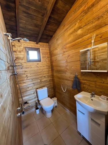 Un baño de madera con inodoro y lavabo. en Лятна каравана “Айтата”, en Kiten