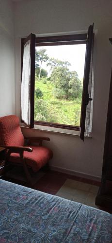 a bedroom with a red chair and a window at Borgo Ingurtosu in Ingurtosu