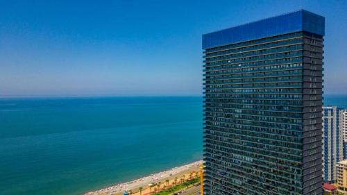 a tall building on the beach next to the ocean at Apartments Beach Tower in Batumi