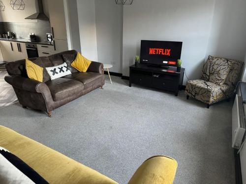 a living room with a couch and a tv at The Lowther Penthouse - 2 Bedrooms - Sleeps 4 in Whitehaven