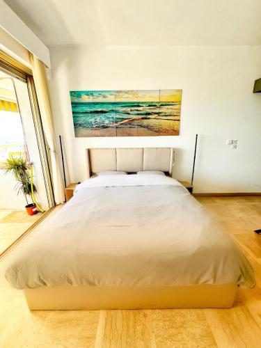 un lit dans une chambre avec un tableau sur le mur dans l'établissement #41 MARINA RIVIERA BAY - Marine Baie des Anges - Studio vue Mer et Port, à Villeneuve-Loubet