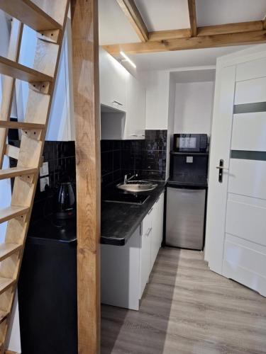 a kitchen with a black counter top and a sink at domek nad jeziorem in Budzisław Kościelny