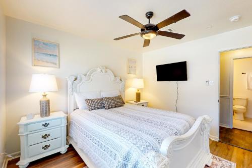 a bedroom with a white bed and a ceiling fan at Pura Vida in Pass Christian