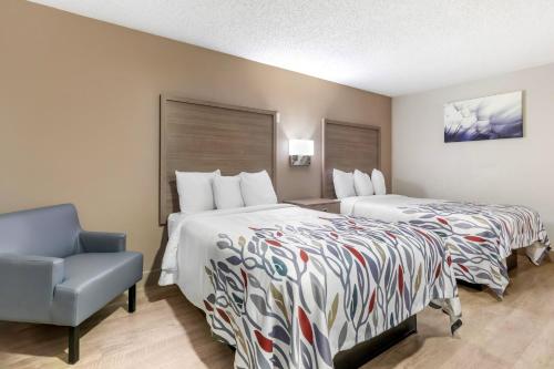 a hotel room with two beds and a blue chair at Red Roof Inn & Suites Newport News in Newport News