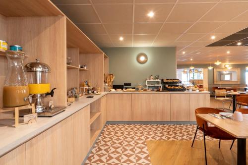 a restaurant with a counter and tables and chairs at Sure Hotel by Best Western Caen Memorial in Caen