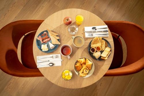 a round wooden table with breakfast foods on it at Sure Hotel by Best Western Caen Memorial in Caen
