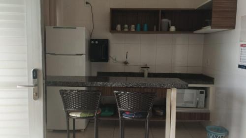 una cucina con bancone, 2 sedie e frigorifero di Hotel Lacquaa Diroma Fogão até 5 pessoas Piscinas 24h a Caldas Novas