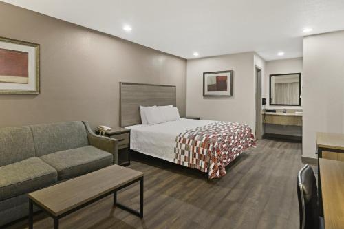 a hotel room with a bed and a couch at Red Roof Inn & Suites Irving - DFW Airport South in Irving