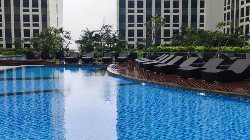 una piscina de hotel con tumbonas y edificios en BAGUSROOM CHADSTONEPOLLUX, en Kedungg