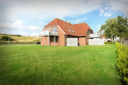 a brick house with a green lawn at Neu seit 2023 FeWo No 3 Friesenhuus Carolinensiel in Carolinensiel
