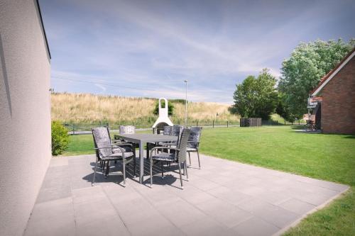 a table and chairs on a patio with a lawn at Neu seit 2023 FeWo No 3 Friesenhuus Carolinensiel in Carolinensiel