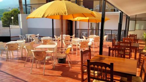 a restaurant with tables and chairs and a yellow umbrella at Hotel La Galera del Mar - Altea in Altea