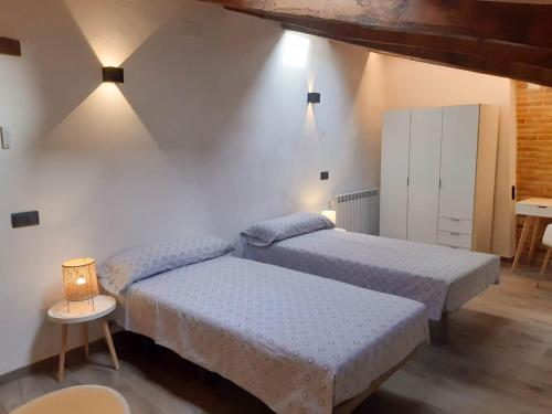 ein Schlafzimmer mit 2 Betten und einem Tisch mit einer Lampe in der Unterkunft Niu de Queralt in Vic