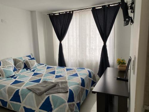 a bedroom with a blue and white bed and a window at Tunja Magic Habitación in Tunja