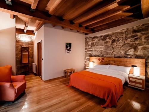 een slaapkamer met een bed en een stenen muur bij Aldea Rural Pazos De Arenteiro in Pazos de Arenteiro