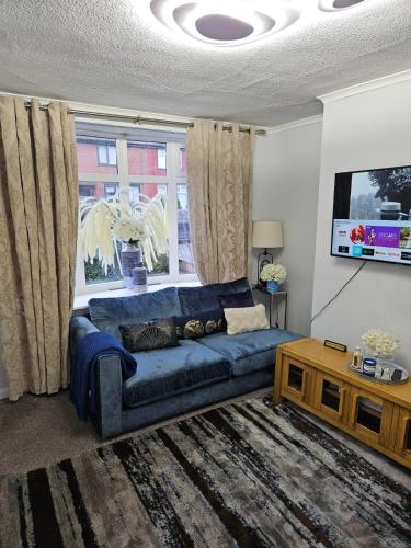 a living room with a blue couch in front of a window at Beautiful Home from Home in Manchester in Manchester