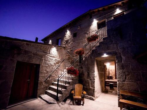 a stone building with a staircase and a chair at Aldea Rural Pazos De Arenteiro in Pazos de Arenteiro