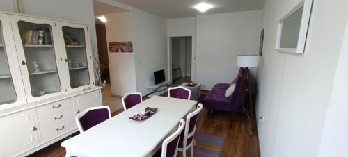 a dining room with a white table and purple chairs at Lovely square apartment Purple Velvet 43 Macedonia Stree in Skopje