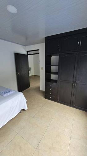 伊瓦格的住宿－Denier House Guabinal Apto 2，一间卧室配有黑色橱柜和一张床