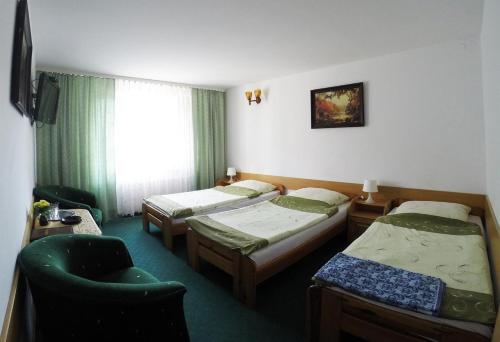 ein Hotelzimmer mit 3 Betten und einem Stuhl in der Unterkunft Vanillia in Siestrzeń