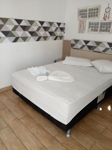 een slaapkamer met een groot bed met witte lakens bij Hotel Villa De Carli Beach in Rio Grande