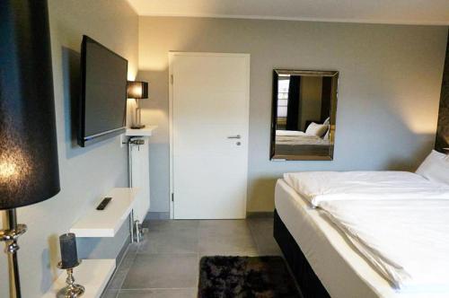 a bedroom with a white bed and a mirror at Huus am Meer in Norddeich