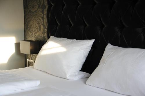 a bed with two white pillows and a black headboard at Huus am Meer in Norddeich