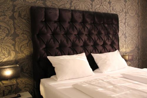 a bed with a black headboard and white pillows at Huus am Meer in Norddeich