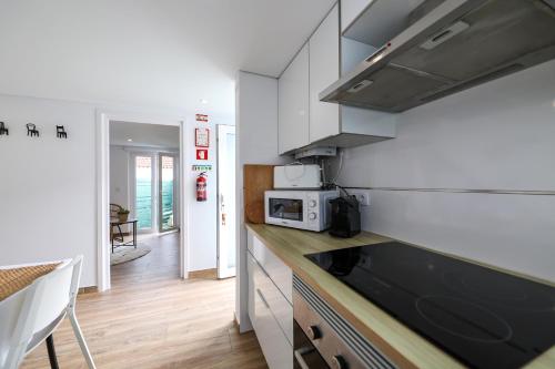 a kitchen with white cabinets and a counter top at Casas com Amoras in Serra da Pescaria in Famalicão