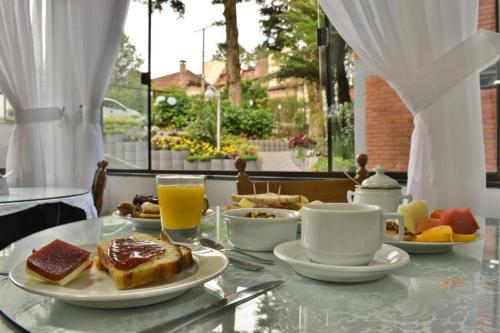 a table with a breakfast of toast and coffee and orange juice at Pousada do Mel in Gramado