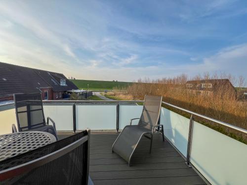 a balcony with two chairs and a table and a view at Huus am Meer in Norddeich